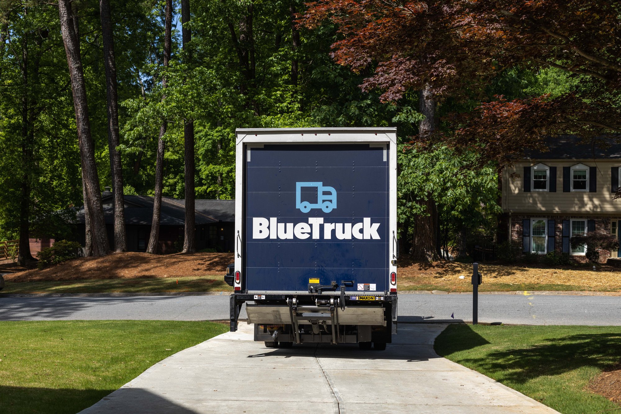 Blue Truck residential furniture delivery truck backing up to customer house Blue Truck residential furniture delivery truck backing up to customer house